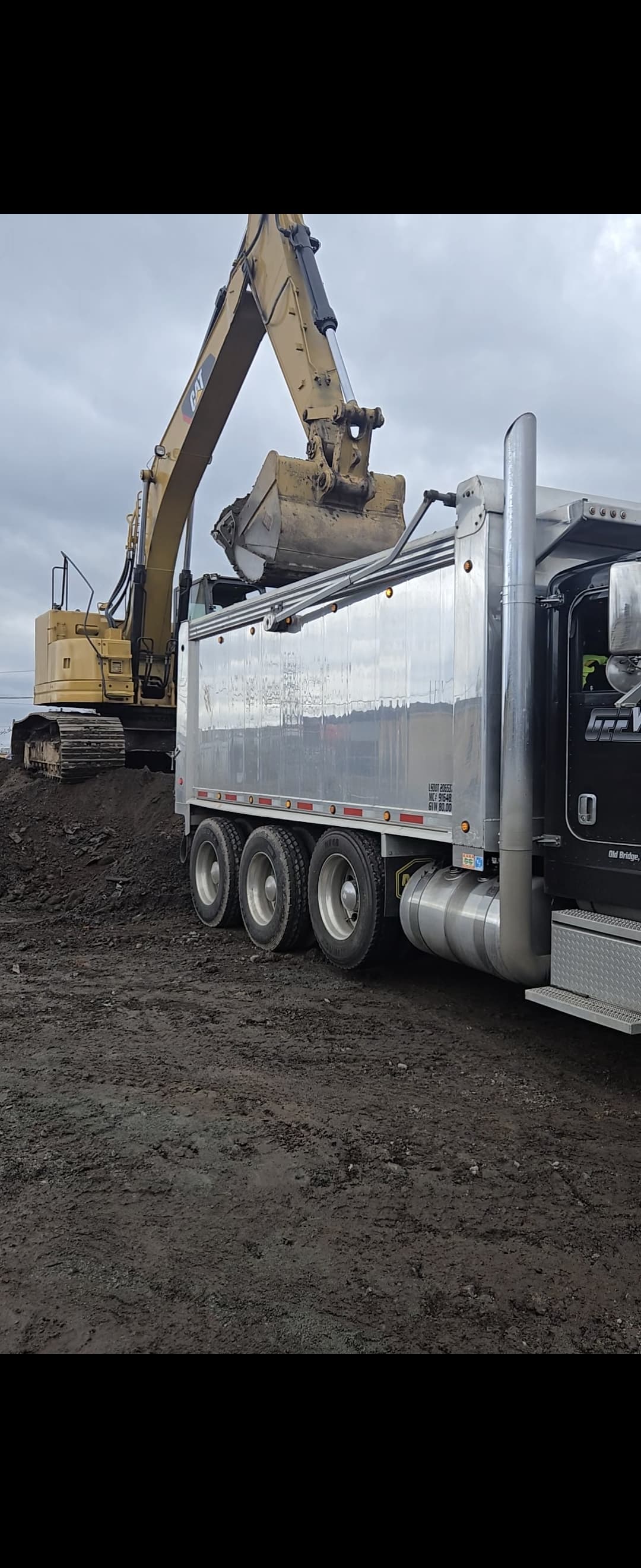 large yellow CAT excavator loading a dump truck
