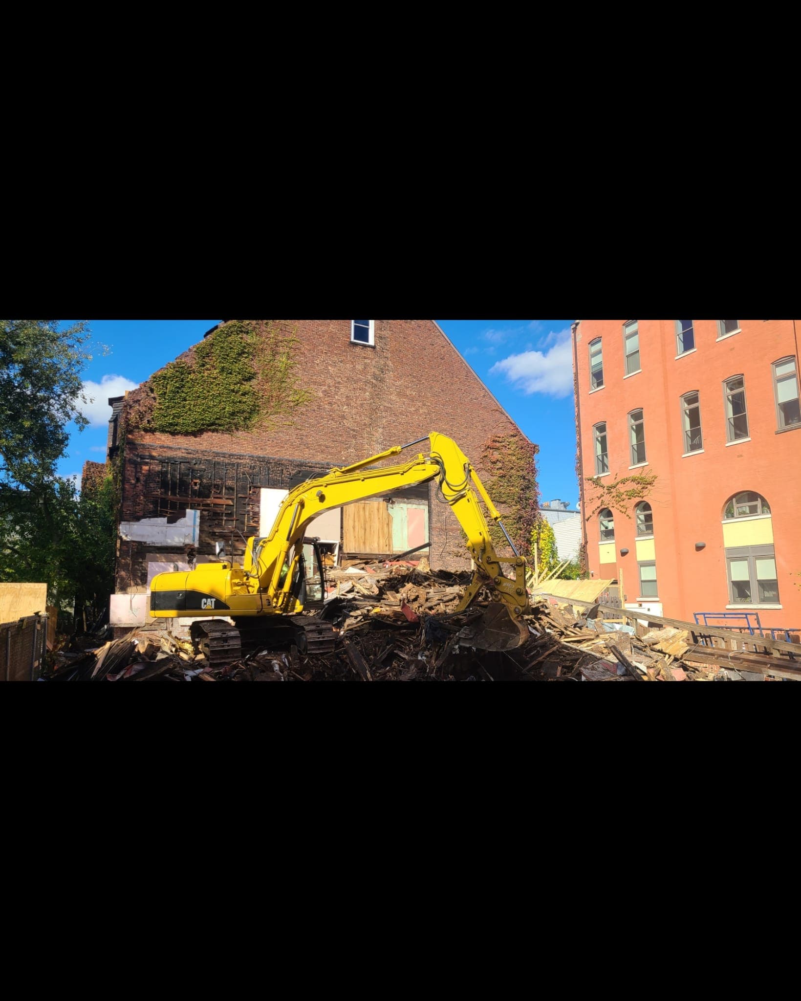excavator working near a red brick building